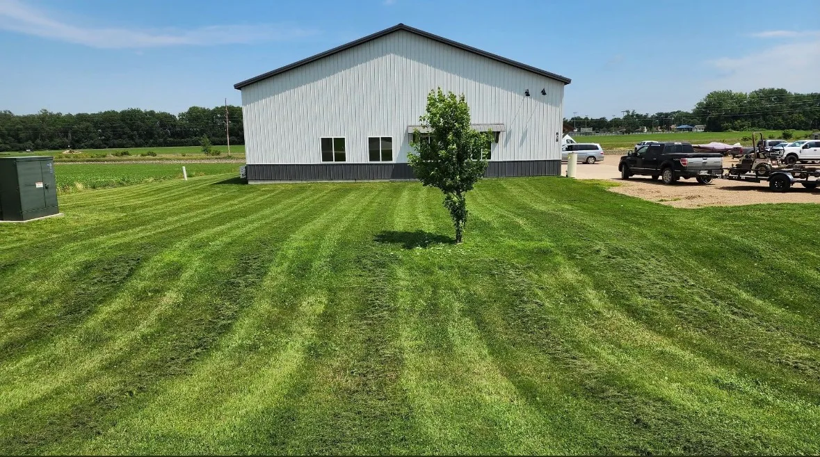 Parallel mowing stripes across a lawn beside a light-colored building